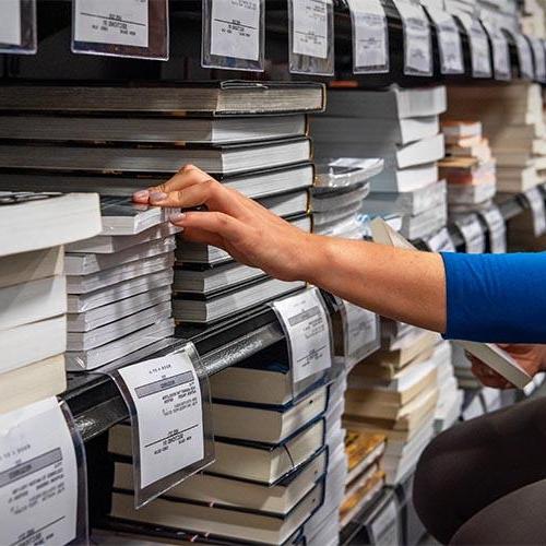 Hand reaching for a textbook in the bookstore.